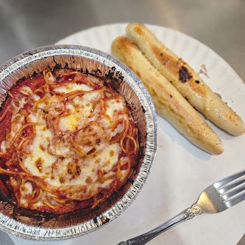 Spaghetti with melted cheese and breadsticks.
