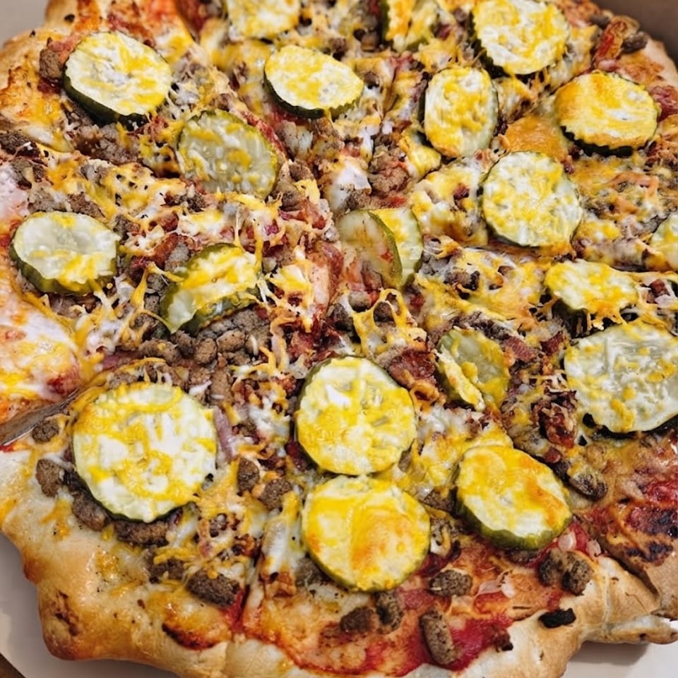 Bacon Cheeseburger pizza topped with pickles and melted cheese.