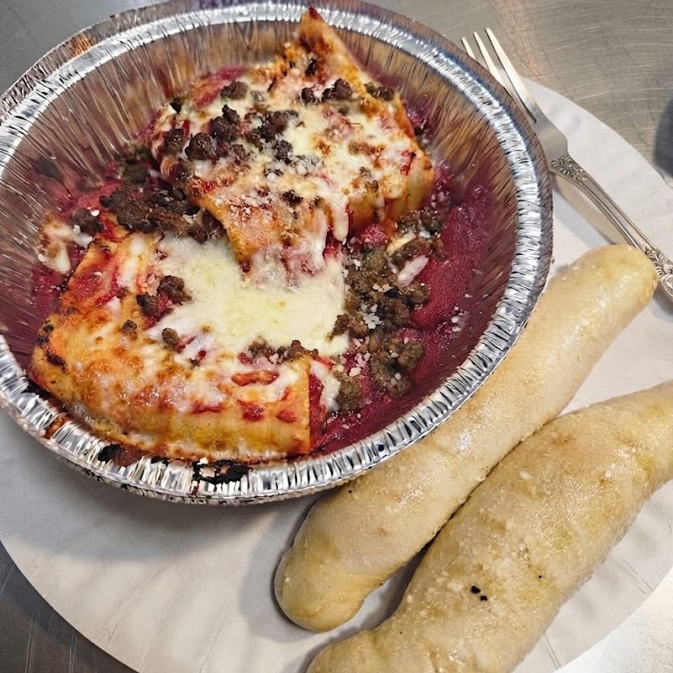 Baked Lasagna served with breadsticks.